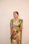 Portrait of a smiling woman wearing a deep peacock green kurti with gold accents.