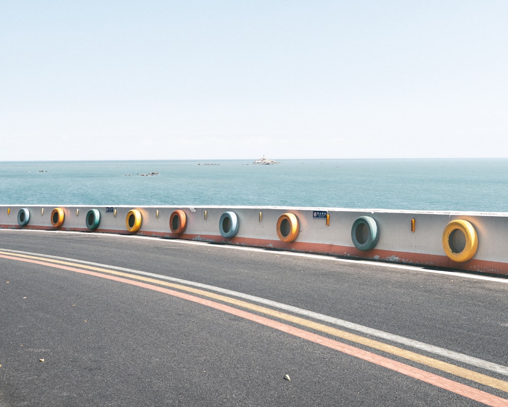 a road with a railing and a body of water in the background