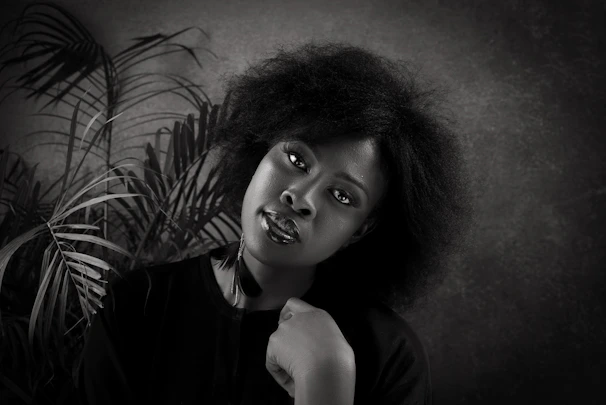 Portrait of Ginelle Reynolds, a confident Black woman with warm, inviting eyes, set against a soft beige background.