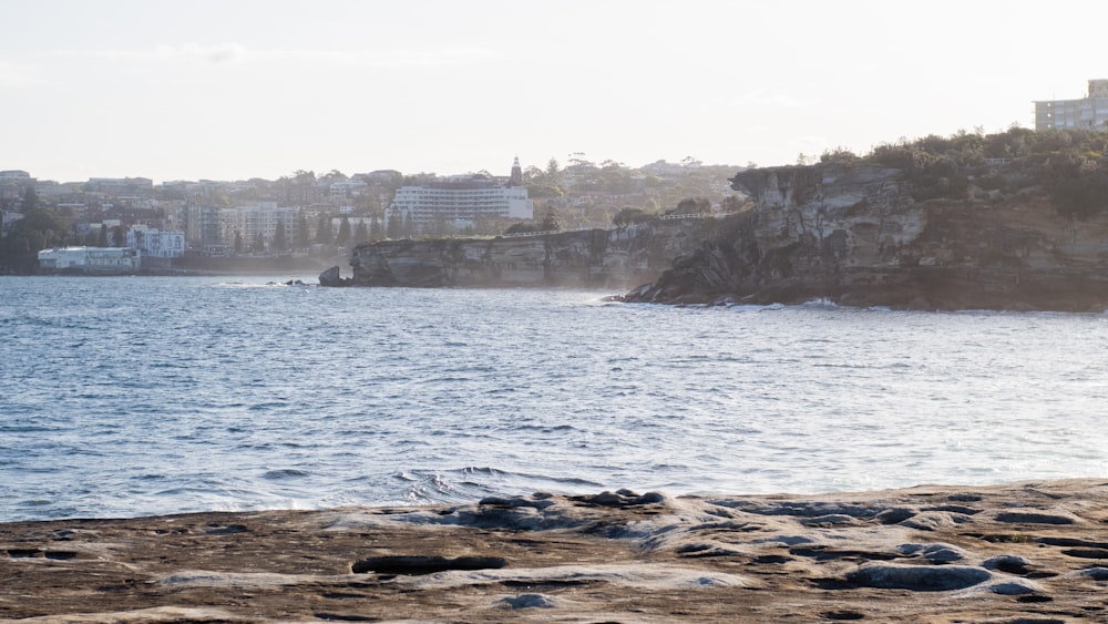 a rocky beach with buildings on the shore