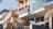 Modern residential buildings with large glass windows and brick facades are positioned on a rocky hill. The structures feature contemporary architectural elements such as balconies with glass railings. The use of natural rock and wood adds to the aesthetic.