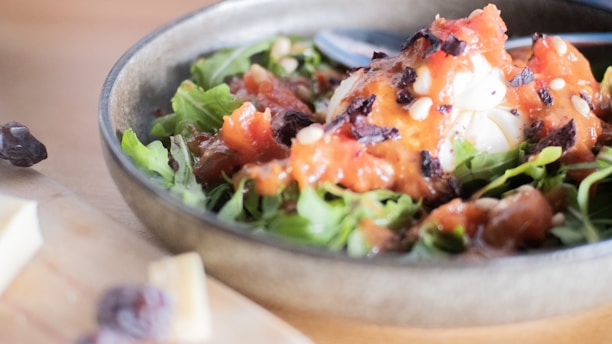 Close-up of a person preparing a vibrant salad with fresh greens and dressing.