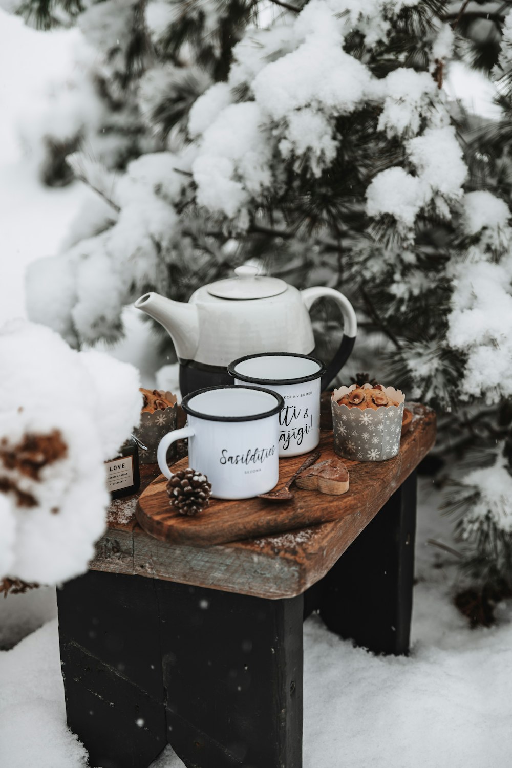 a table with cups and a teapot on it in the snow