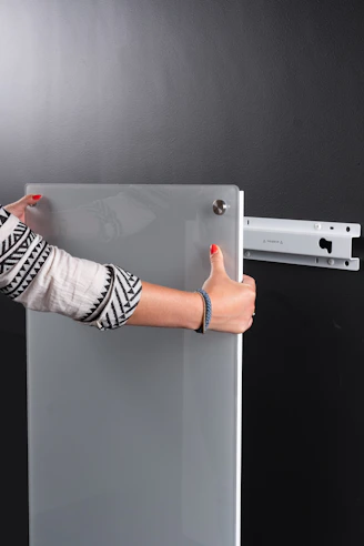 Close-up of skilled hands bonding clear acrylic sheets in a bright workshop.