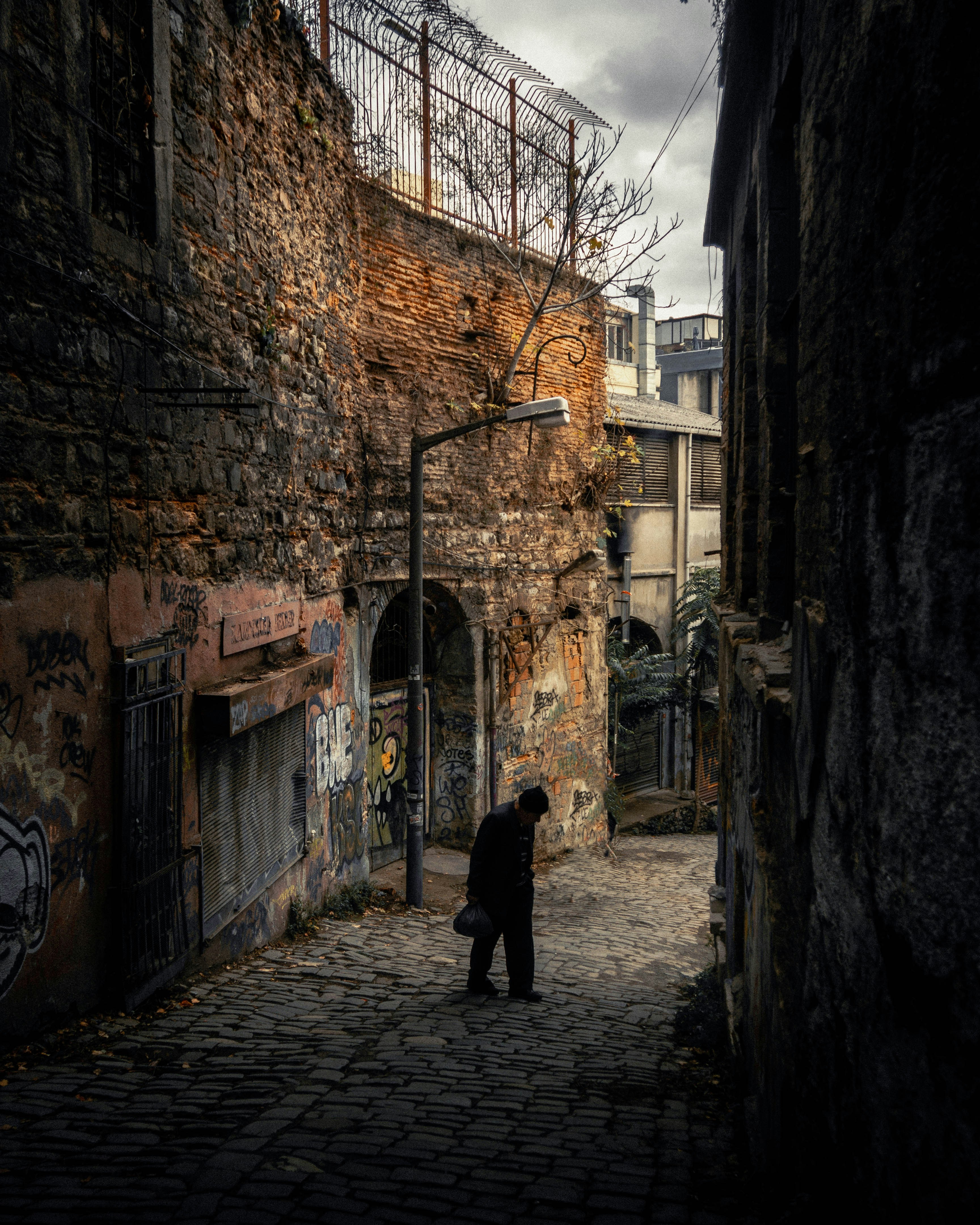 uma pessoa andando por uma rua de paralelepípedos entre dois edifícios
