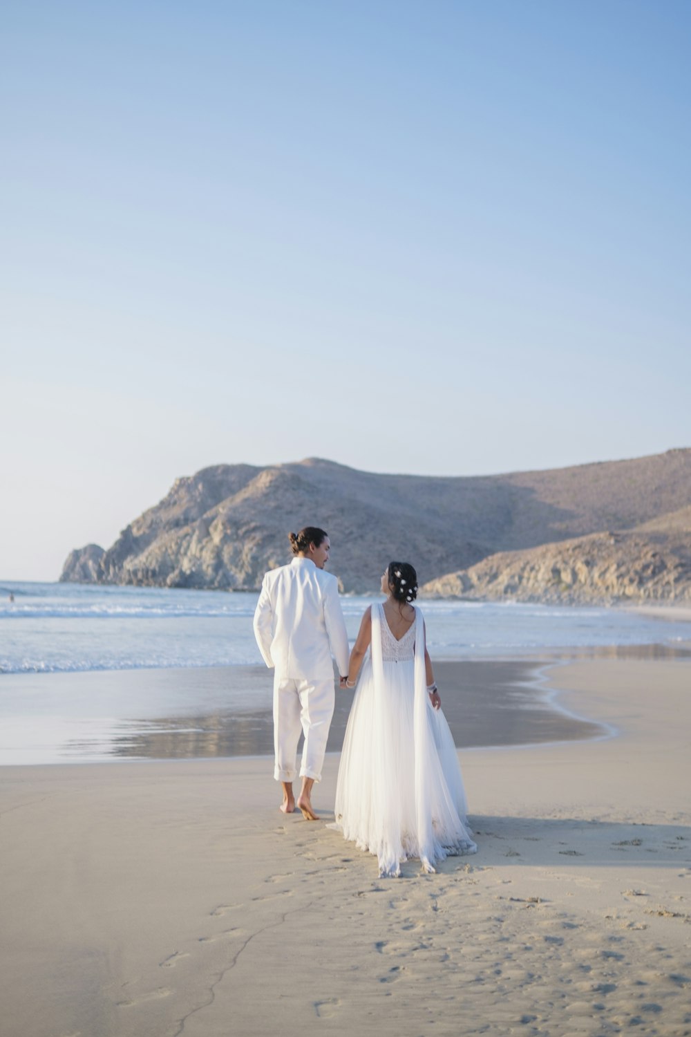 Ein Mann und eine Frau in Hochzeitskleidung am Strand