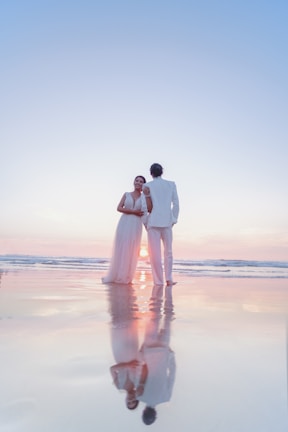 An elegant couple enjoying a private beach dinner in the Maldives, illuminated by soft golden lights.