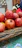 A basket filled with vibrant red pomegranates resting on rustic wooden farm table.