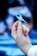 A hand delicately holding a blue awareness ribbon with the background softly blurred to focus on the ribbon.