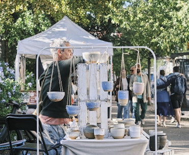 Artisan vendor displaying handmade pottery and crafts under a bright canopy.