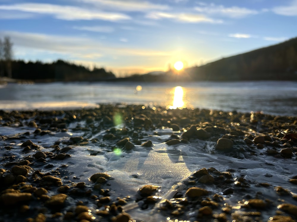 a rocky beach with the sun setting