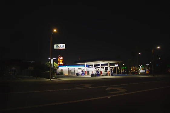 A friendly gas station at night with bright lights and a convenience store visible.