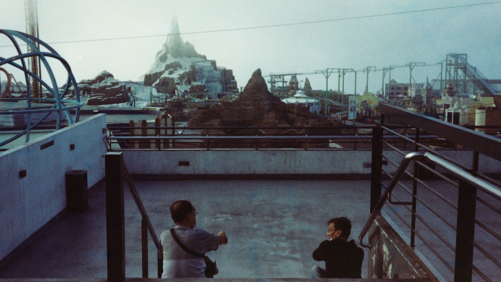 two boys sitting on a bridge