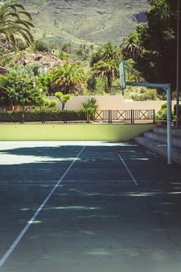 a tennis court with trees and a hill in the background