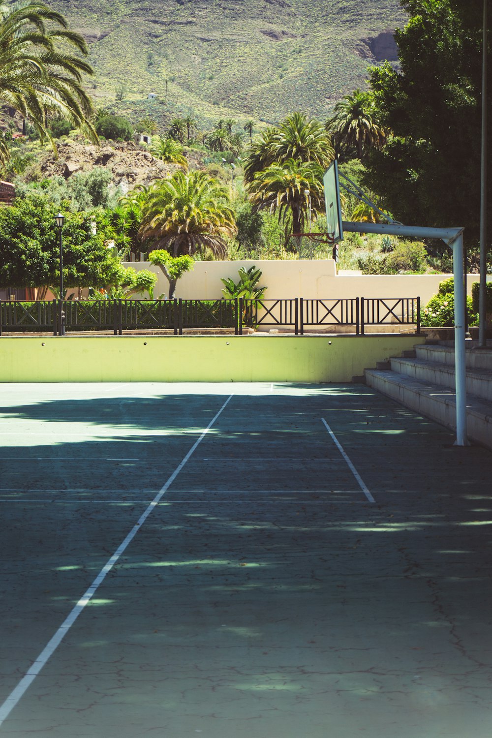 a tennis court with trees and a hill in the background