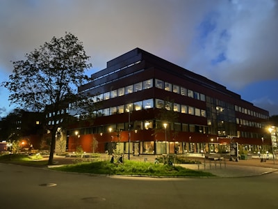 A modern hospital building illuminated at dusk along the highway.