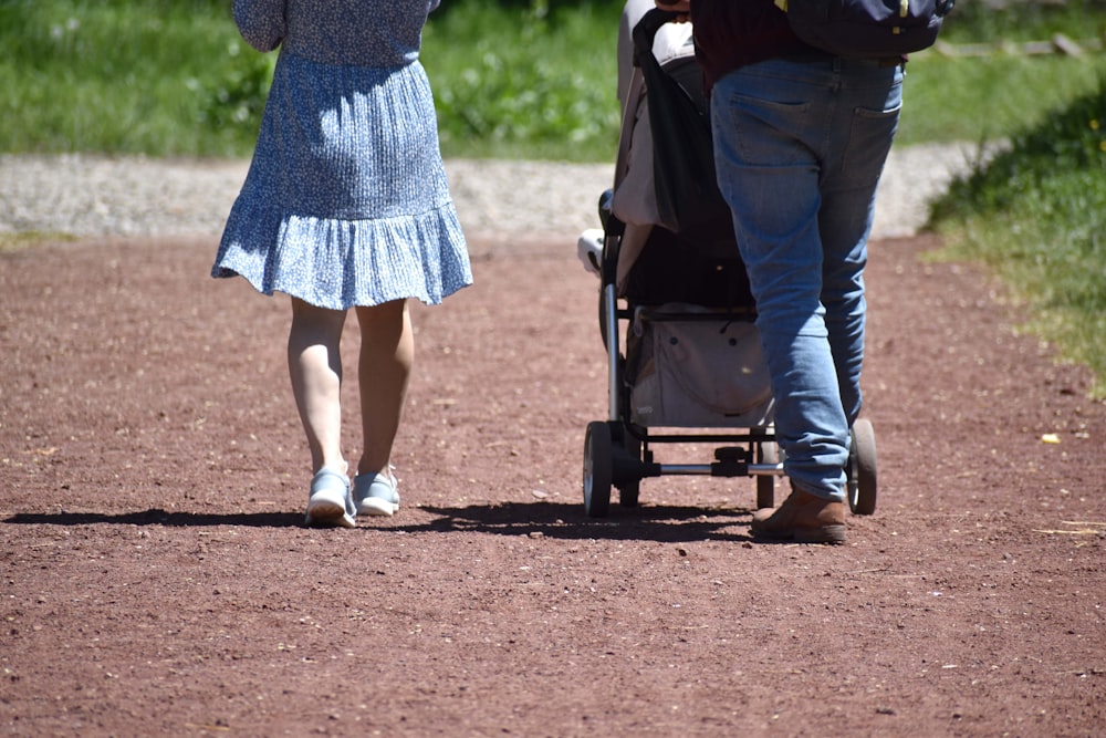 um homem e uma mulher andando com carrinho de bebê