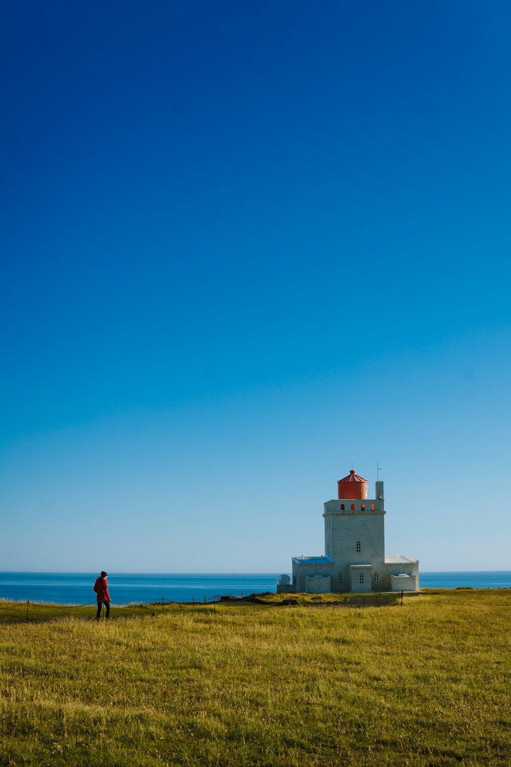 a person standing on a grassy hill by a lighthouse