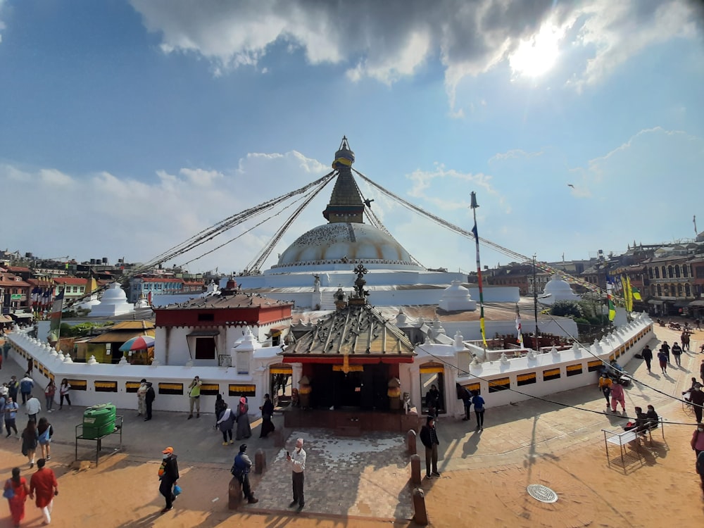 un gruppo di persone che camminano intorno a un grande edificio con un tetto a cupola con Boudhanath sullo sfondo