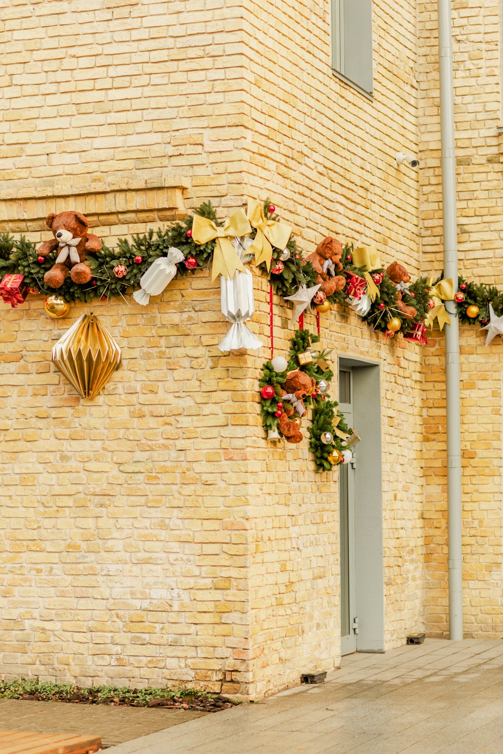 a brick building with a large wreath of flowers from the roof