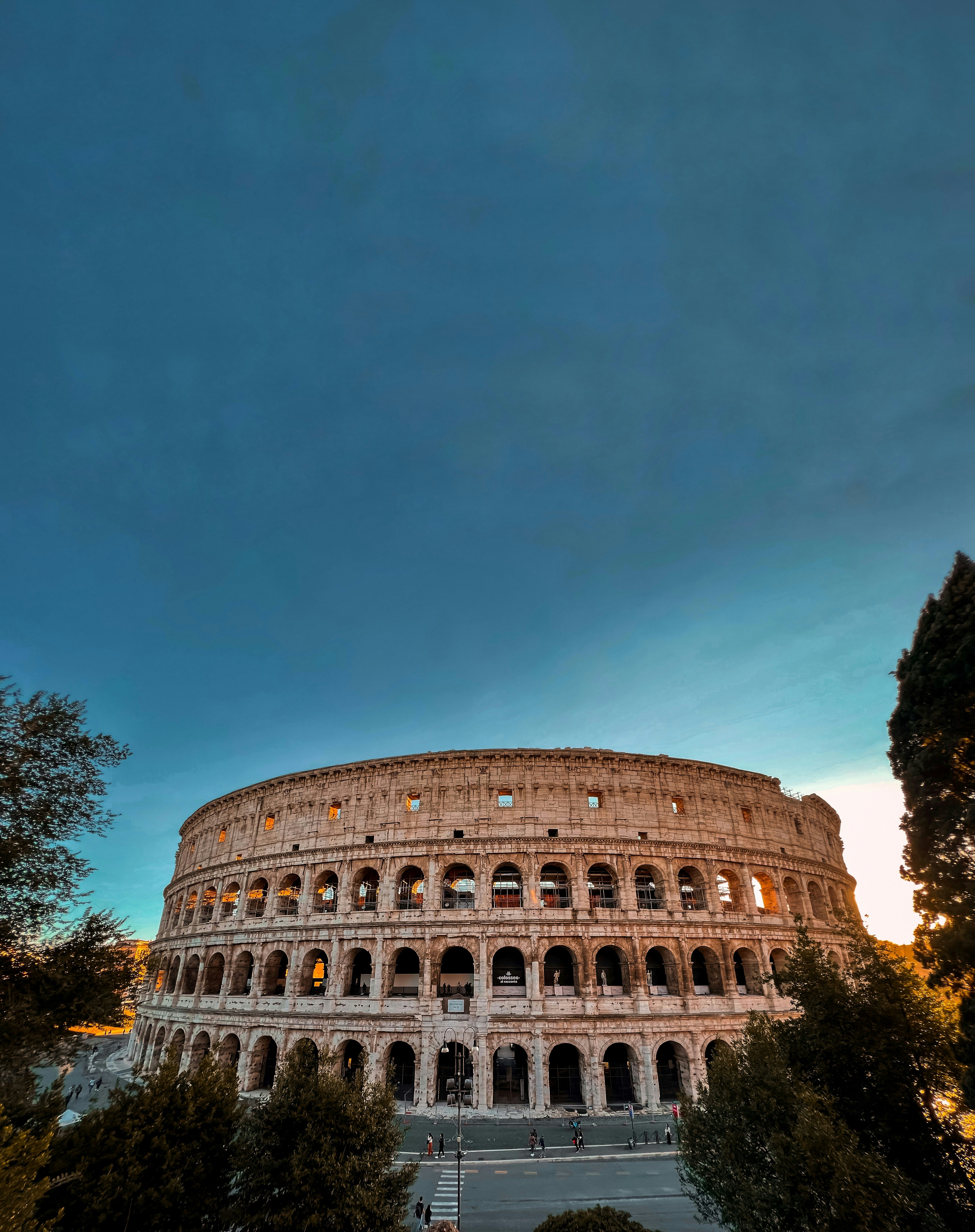 Evening scene of the Colosseum glowing warmly under the setting sun.
