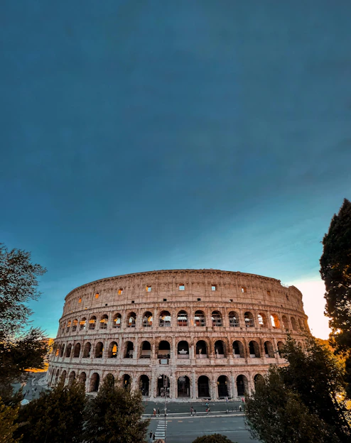 Evening scene of the Colosseum glowing warmly under the setting sun.