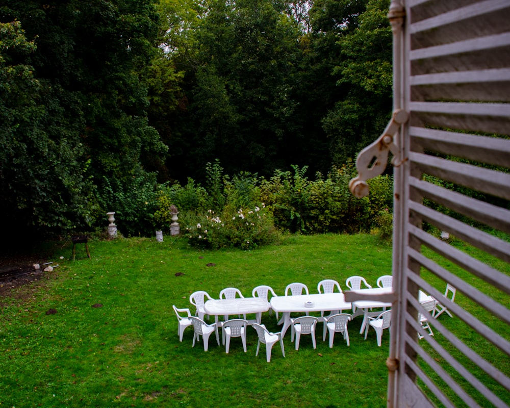 a row of white chairs in a yard