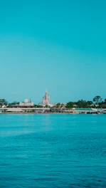 A vibrant collage showing Walt Disney World castle, Universal Studios globe, and a luxury cruise ship sailing under a clear blue sky.