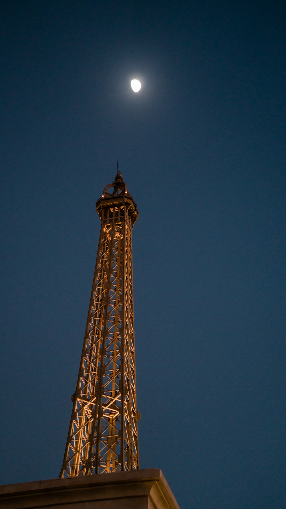 a tall metal tower with a moon in the sky