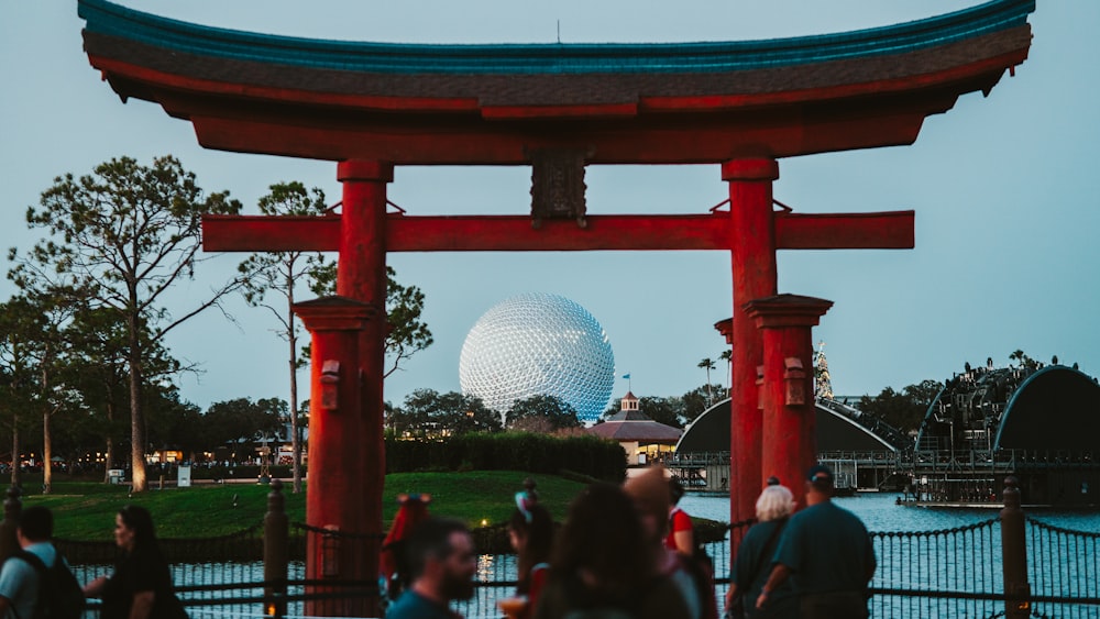 um grupo de pessoas de pé sob uma estrutura vermelha com um globo ao fundo