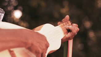 A smiling student practicing samba chords on a cavaquinho outdoors