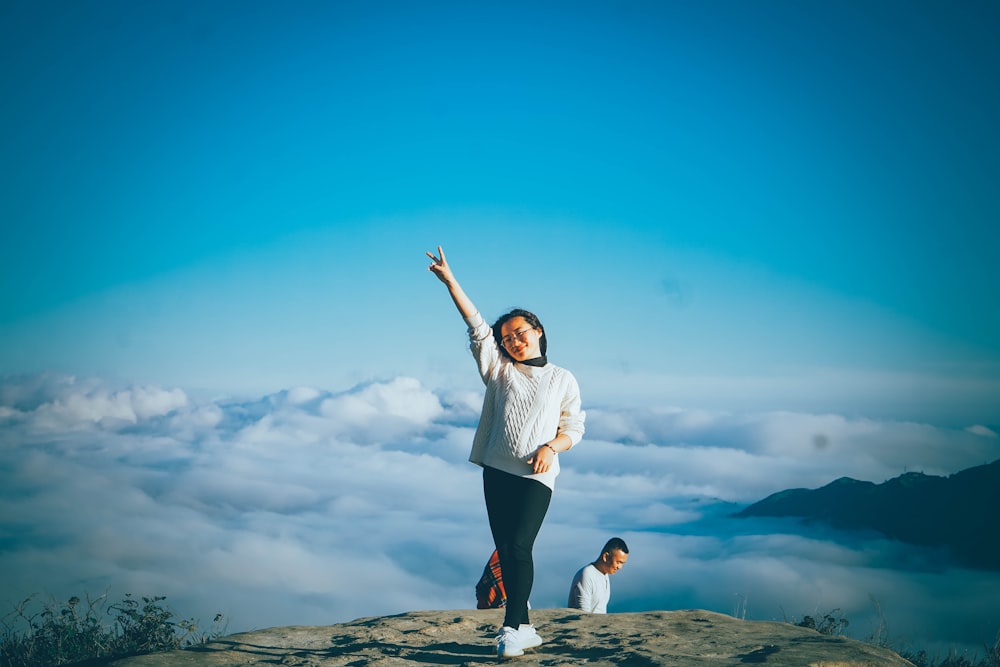 a woman standing on a rock with a man sitting on the side