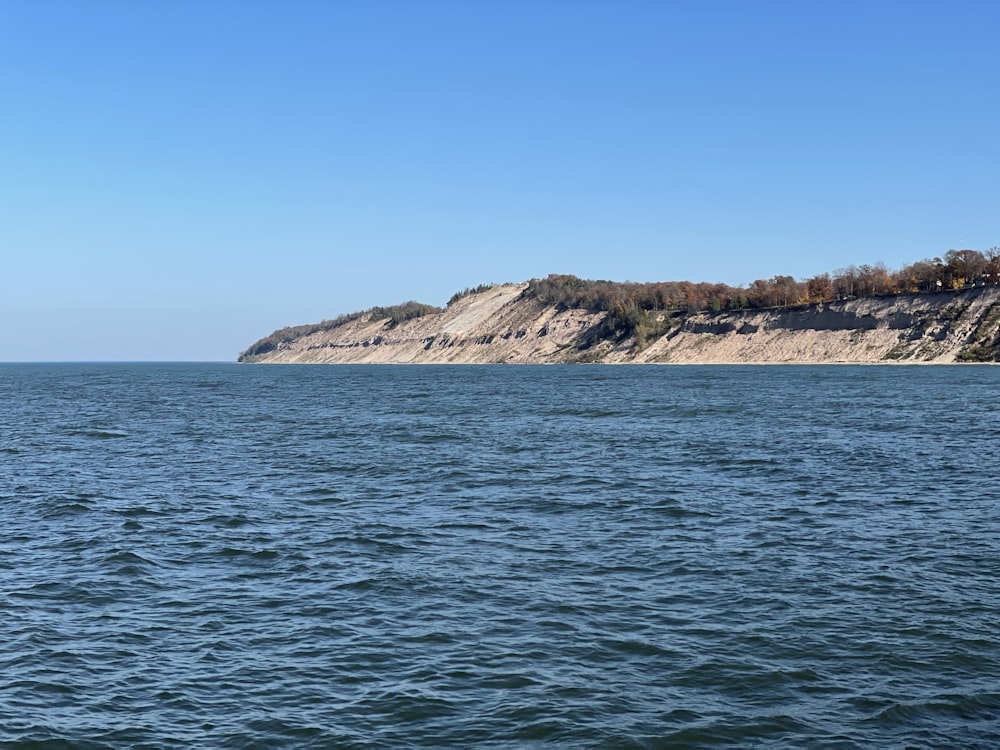 a body of water with a rocky hill in the background