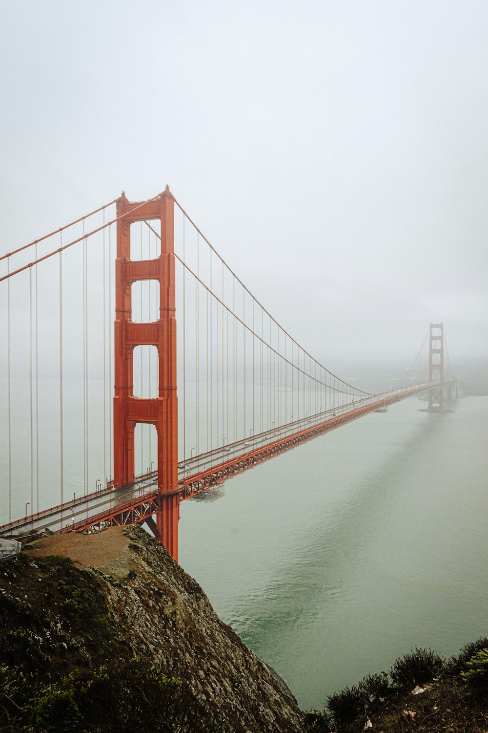 a large red bridge over water with Golden Gate Bridge in the background