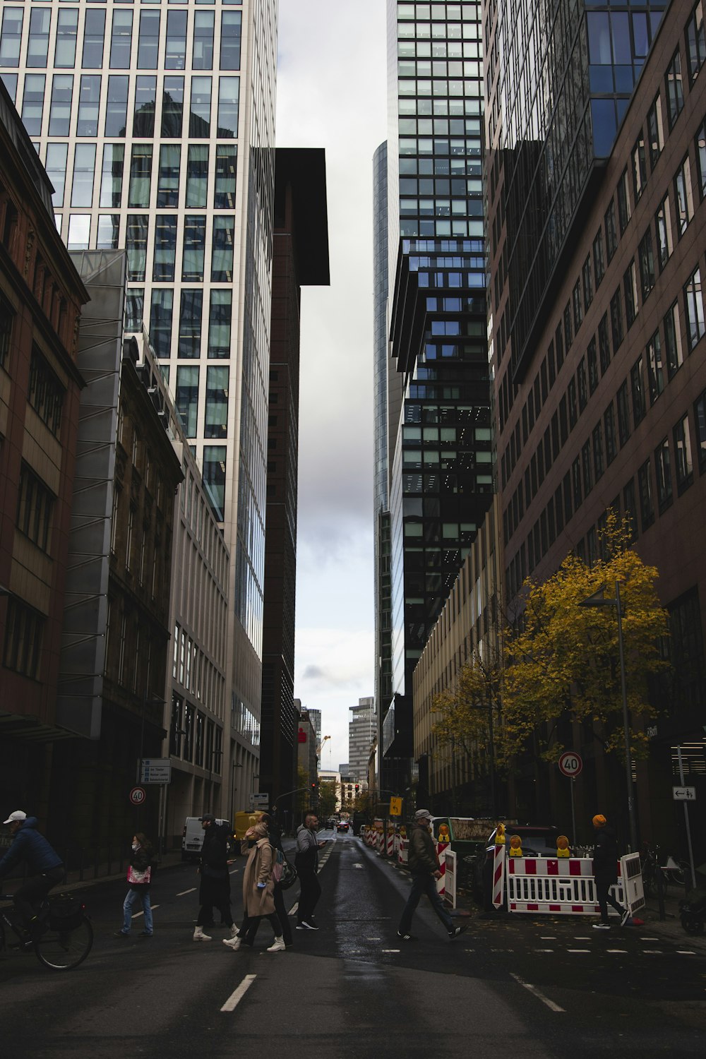 a group of people walking on a street between tall buildings