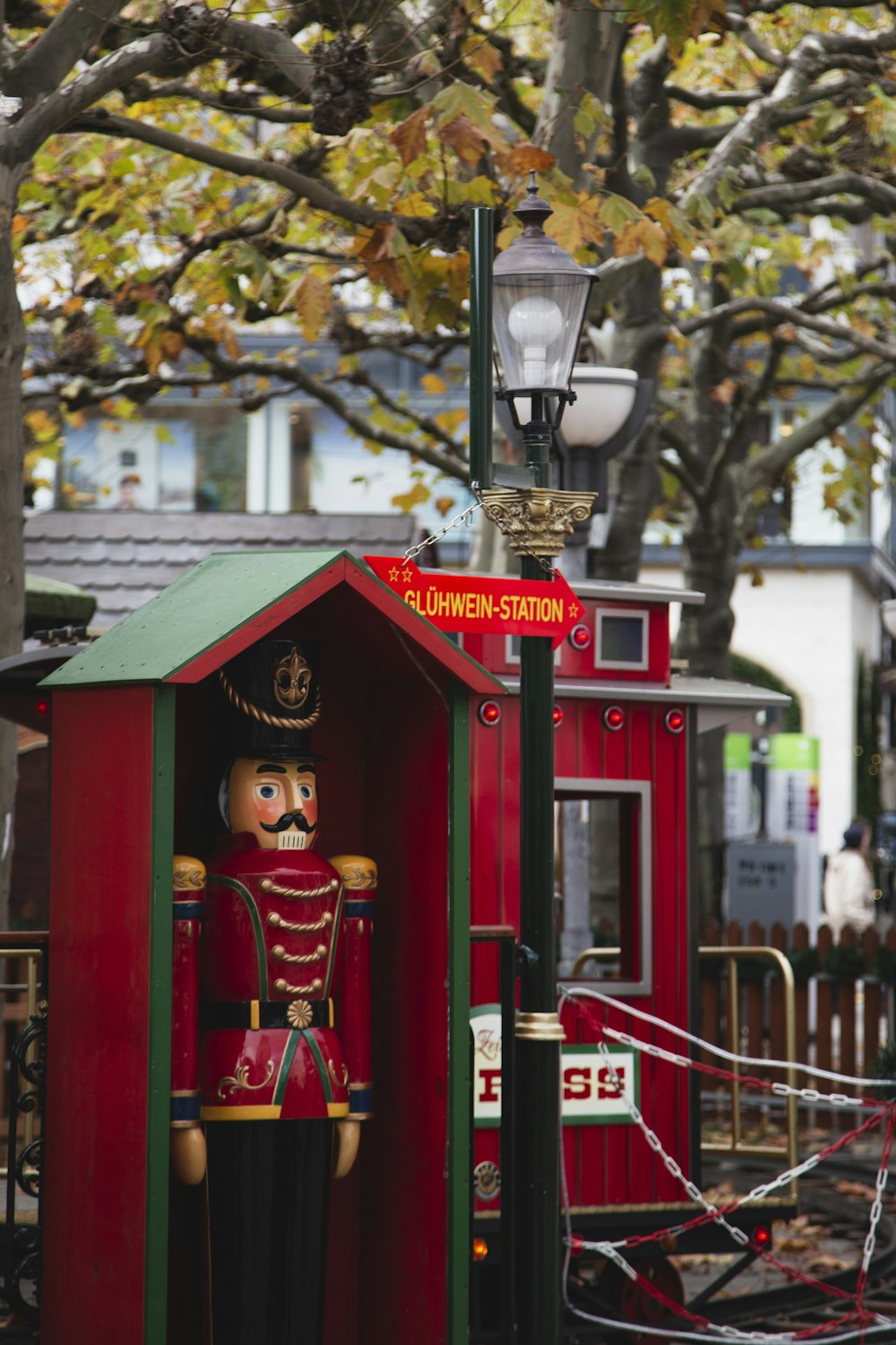 a red telephone booth with a lamp post and a tree