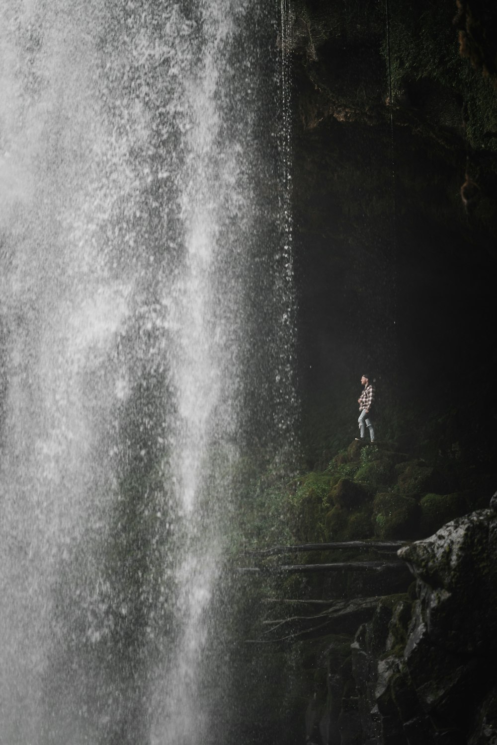 a person standing on a rock near a waterfall