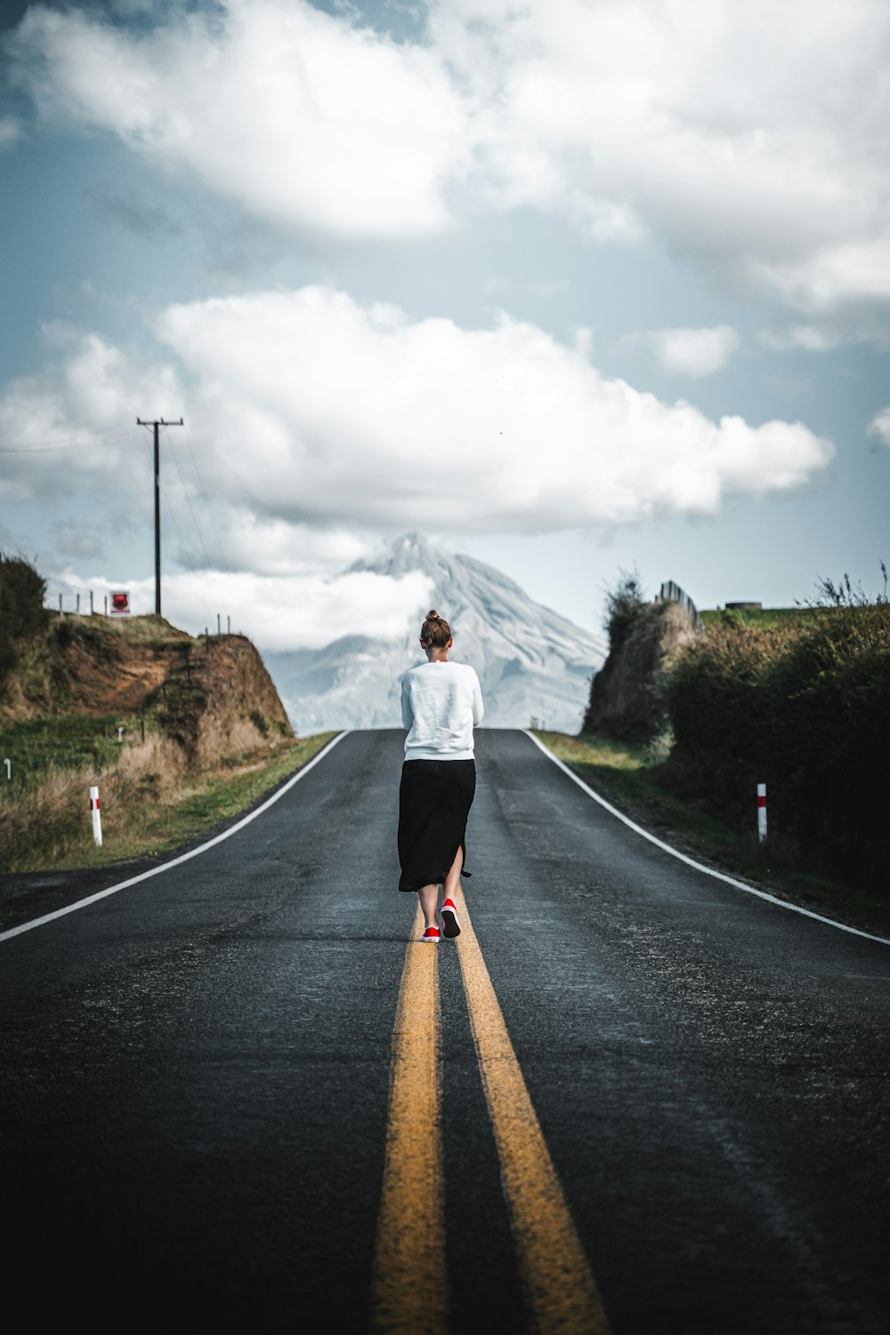 a man standing on a road with a mountain in the background