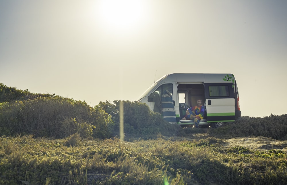 a group of people sitting in a van in a field