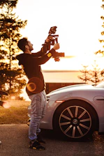 A professional photographer setting up a camera outside a charming suburban home during golden hour.
