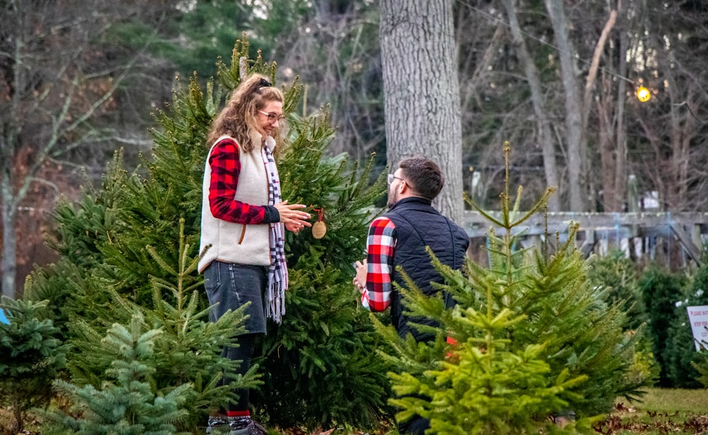 a man and woman standing next to a christmas tree