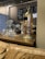 A vintage-style coffee machine with a polished copper finish stands prominently on a wooden table. Nearby, there are coffee brewing equipment like drippers and carafes arranged neatly. The background features brick walls and metallic pipes, giving an industrial vibe. A chart related to coffee is mounted on the wall.