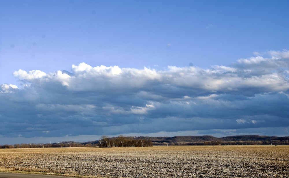 a large open field with clouds in the sky