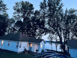 Exterior view of the cottage at dusk with glowing windows and surrounding trees.