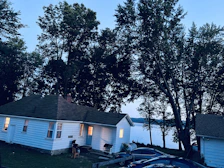 Exterior view of the cottage at dusk with glowing windows and surrounding trees.