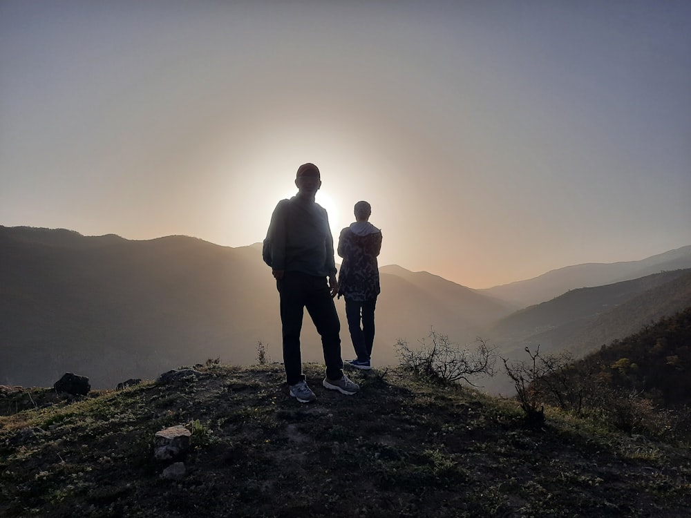 two people standing on a hill