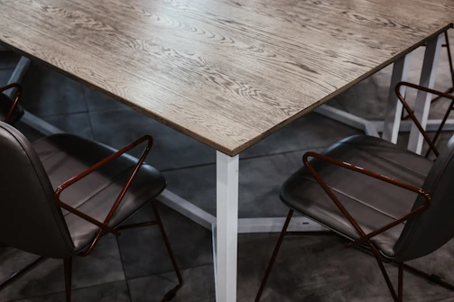 Team members dismantling a wooden dining table with precision in a modern villa setting.