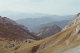 A serene mountain landscape with a winding trail leading to the horizon.