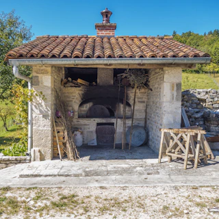A rustic stone oven glowing with fiery embers, ready for outdoor cooking on a concrete terrace.