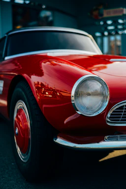 A close-up shot of a vintage car's headlight reflecting the surrounding Ticino landscape at sunset.